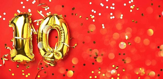 Illustration mit goldener 10 in Form von Luftballons auf rotem Hiuntergrund