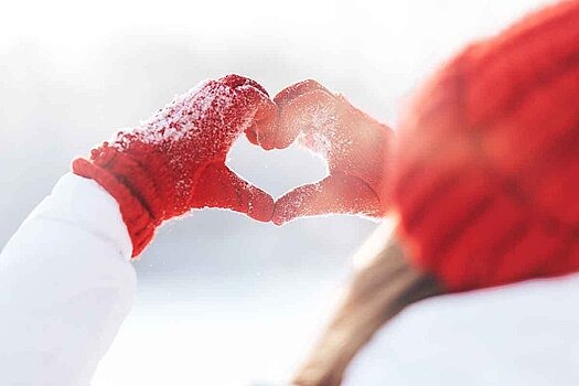 Frau mit roter Mütze und roten Handschuhen formt mit Händen ein Herz