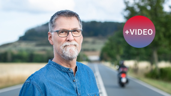 Jörg Fricke steht mitten auf einer Straßenfahrbahn. Im Hintergrund fährt ein Motorrad davon.