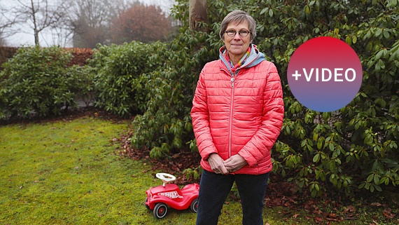 Nicola Ackermann-Aachner steht in einem Garten. Hinter ihr steht ein Bobbycar.