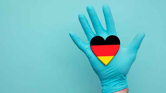 Illustration einer geöffneten Hand in einem blauen Einweghandschuh mit einem Herz in schwarzrotgold 